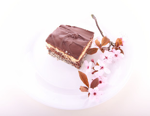 Piece of cake on a plate with a twig covered with flowers