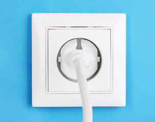 White electric socket with plug on the wall