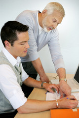 Obraz premium Older man pointing out something in a document to a colleague