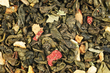 green tea with orange peel and strawberries as background
