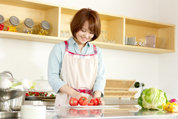 Beautiful young woman in kitchen making salad. Portrait of asian