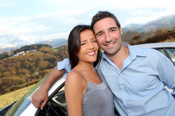 Couple standing by car on the road