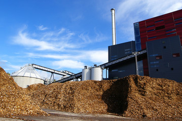 bio power plant with storage of wooden fuel against blue sky