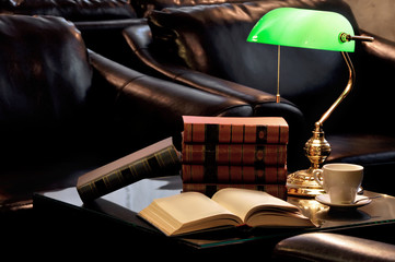 Electric green table lamp and books with armchair and cup