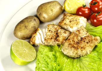 Fried white fish on a plate, potatoes and lettuce