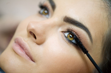Woman applying mascara on her long eyelashes