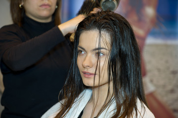 Fototapeta premium Pretty lady sitting while hairdresser dries her hair