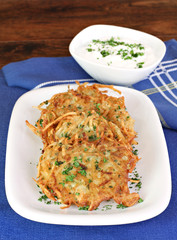 Potato Latkes and sour cream, vertical.