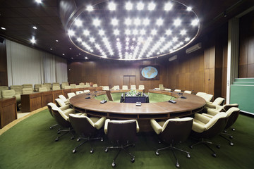 Auditorium with round oak table, beige armchairs around it