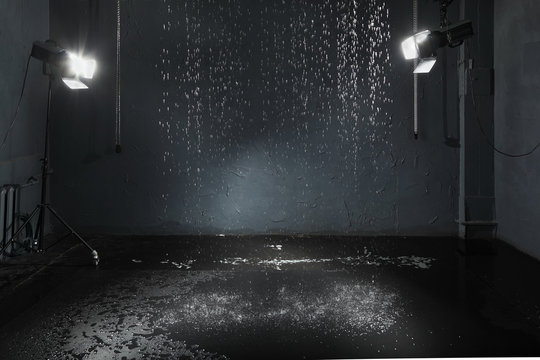 Rain in studio with black walls, lighting system
