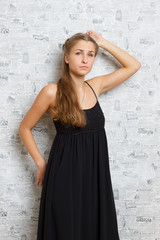 Fototapeta premium Beautiful girl in a dress near the wall