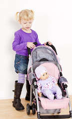 little girl playing with a doll and a stroller