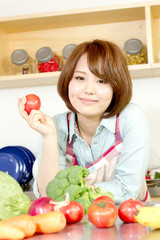 Beautiful young woman in kitchen making salad. Portrait of asian