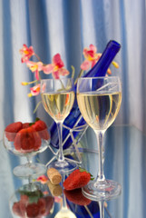 Two glasses of wine with red strawberries and orchid