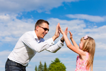 Father is playing with his daughter on a meadow