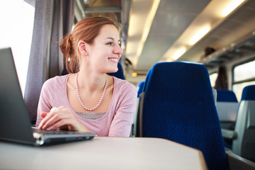 Young woman using her laptop computer while on the train