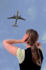 Frau mit Haenden an den Ohren und Flugzeug