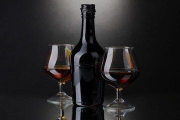 Glasses of brandy and bottle on gray background