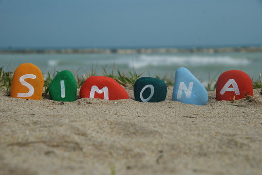 simona, female name on colourful pebbles on the sand