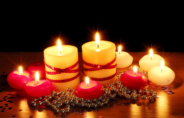Beautiful candles and decor on wooden table on black background