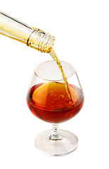 Filling a glass of brandy isolated on white