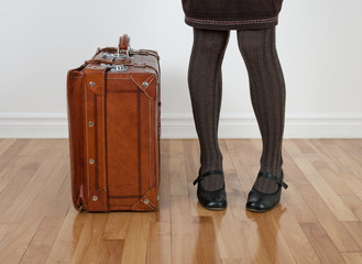Woman in brown stockings standing near vintage suitcase