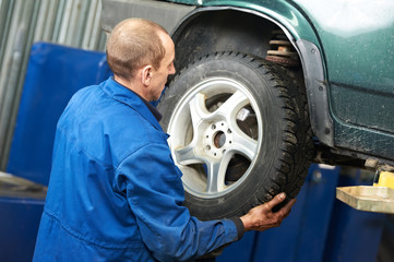 mechanic installing car wheel at service station