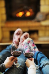 Young romantic couple sitting on sofa in front of fireplace at h