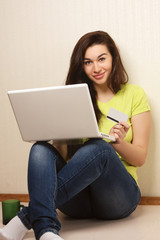 A young girl with a laptop and a credit card
