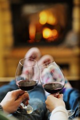 Young romantic couple sitting on sofa in front of fireplace at h