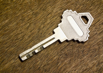 silver key with blank tag wooden background. space for your text