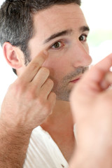 Obraz premium Man in front of mirrror looking at his wrinkles