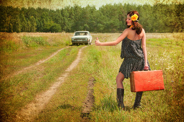 Beautiful brunette with a suitcase in the countryside. Photos in