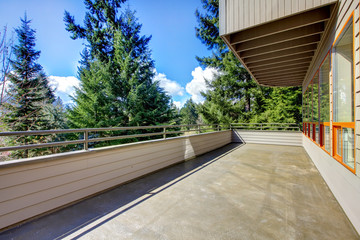 Large balcony with woods view and house.