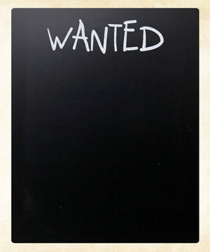 "Wanted" handwritten with white chalk on a blackboard