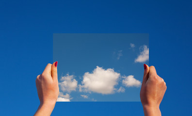 Hands holding a frame with clouds