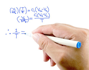 Teacher hand writing a mathematical equation on a white screen.