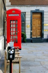 Obraz premium Red telephone box near a bench