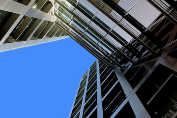Naklejka premium Blue sky peeking from in between architecture buildings