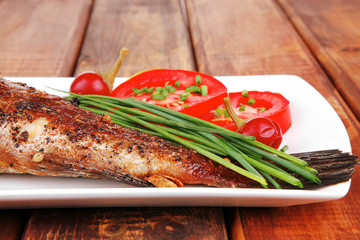 whole fried bass on plate over wood