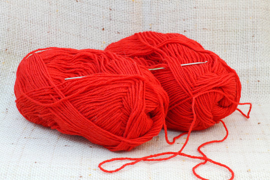 two red balls (clews) of yarn and knitting hook