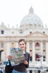 Pretty young female tourist studying a map at St. Peter's square