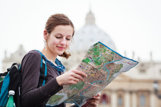 Pretty young female tourist studying a map at St. Peter's square