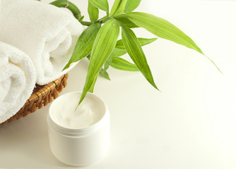 Facial cream, towels and bamboo plant.