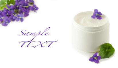 Container of cosmetic cream with violet flowers
