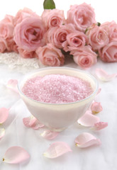 Bowl of bath salt with pink rose on towel background