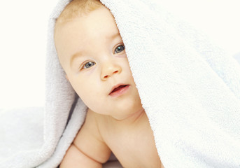 baby is looking from under the towel