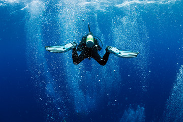 diver swims in air bubbles as in whirlpool