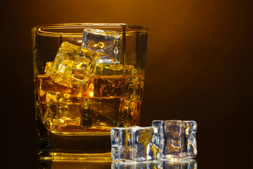 glass of scotch whiskey and ice on brown background