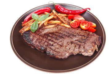 beef steak on dark plate with red hot chili pepper